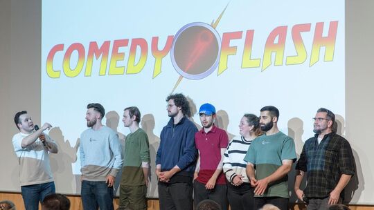 Comedyflash: Der Organisator Dionysis Ghenes (links) mit den sieben Comedians des Abends. Foto: Peter Dietrich Comedyflash: Der Organisator Dionysis Ghenes (links) mit den sieben Comedians des Abends. Foto: Peter Dietrich